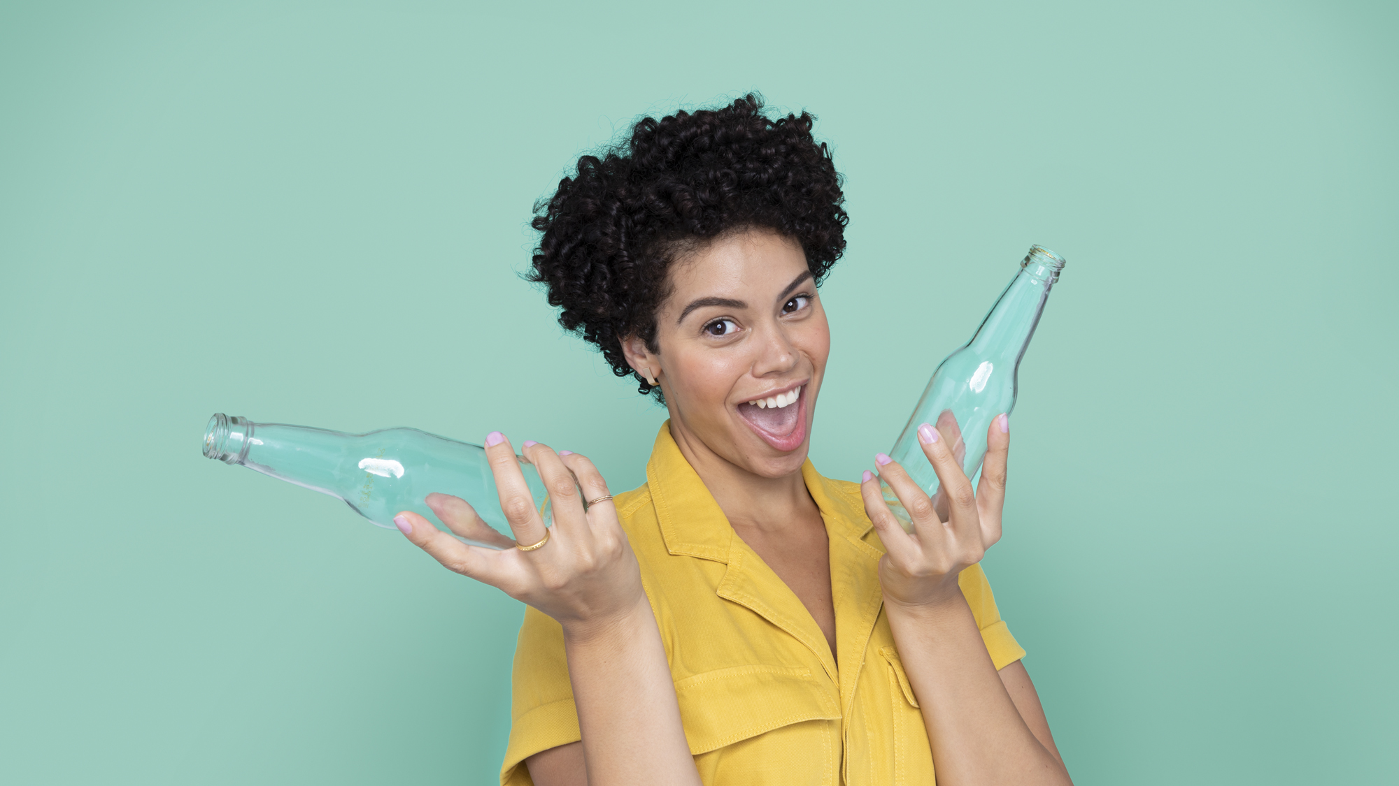 Smilende kvinne som holder opp to glassflasker 